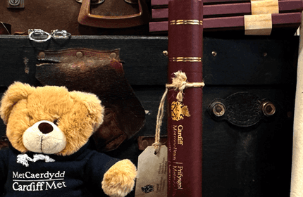 A display of Cardiff Metropolitan University merchandise, including branded plush bears, tote bags, and ties